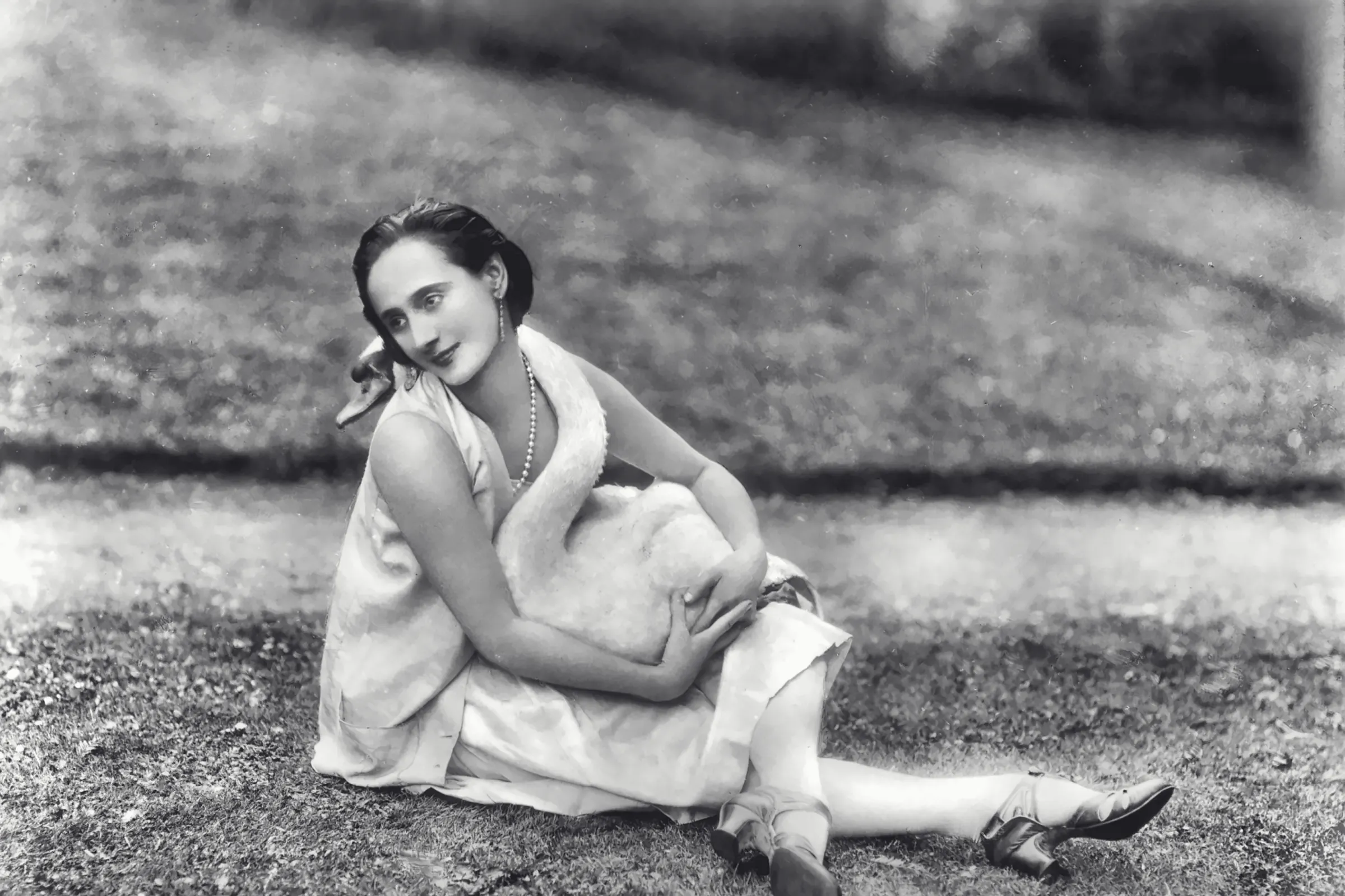 Anna Pavlova zit op het gazon met een witte zwaan op schoot